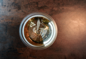 Blick von oben auf ein Getränk mit feinen Bläschen in einem Glas.