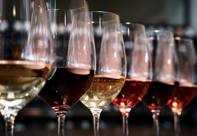 Reihe von Weingläsern mit verschiedenfarbigen Weinen in elegantem Ambiente.