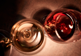 Zwei Weingläser von oben: links hell, rechts rot, auf dunklem Untergrund.