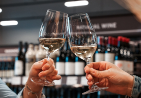 Zwei Weingläser stoßen in einer Weinauslage an.