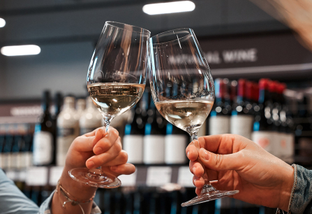 Zwei Weingläser stoßen in einer Weinauslage an.