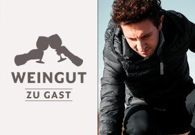 Zwei Weingläser stoßen an, daneben ein Mann in schwarzer Jacke nachdenklich.