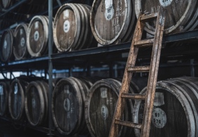 Holzfässer mit Leiter in einem dunklen Lagerraum.