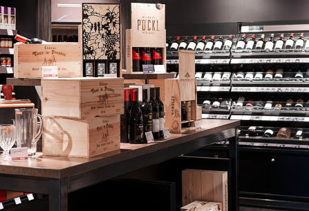 Weinladen mit edlem Holzregal, gefüllt mit dekorativen Weinflaschen und Gläsern.