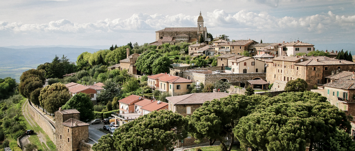 Bergdorf mit Kirche, umgeben von grünen Bäumen und historischem Mauerwerk.