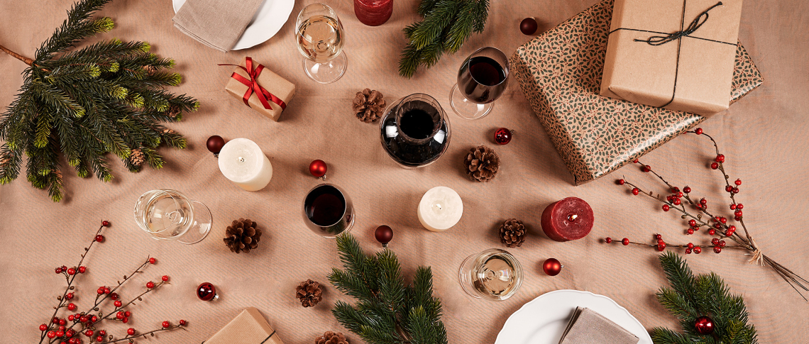 Festlich dekorierter Tisch mit Weihnachtsgeschenken, Tannenzweigen und Kerzen.