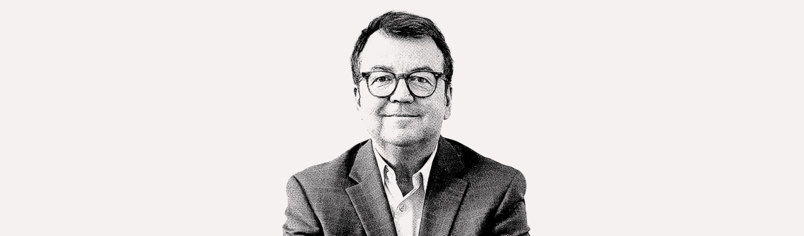Schwarz-weiß Portrait eines Mannes mit Brille im Anzug, auf hellem Hintergrund.