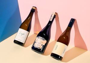 Drei Weinflaschen vor blau-rosa Hintergrund, moderner Schattenwurf.