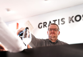 Mann schenkt Getränk in ein Glas hinter einem Tresen ein.