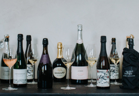 Verschiedene Sektflaschen und Gläser mit Sekt auf einem dunklen Tisch.