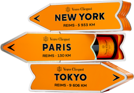 Helle, orangefarbene Schachteln mit Wegweisermotiven, enthalten stilvolle Champagnerflasche.