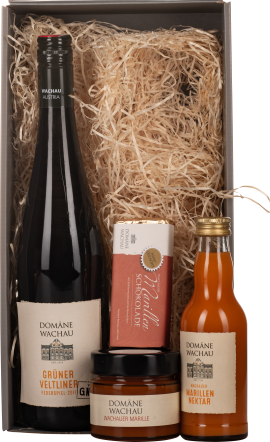 Geschenkset mit Wein, Marmelade, Schokolade und Nektar in Holzwolle-Verpackung.