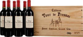 Sechs Flaschen Rotwein mit rotem Korken und elegantem Etikett neben einer dekorativen Holzkiste mit stilisiertem Gebäudeaufdruck.