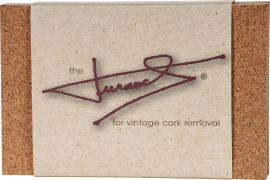 Rechteckige Verpackung mit seitlichen Korkelementen. In der Mitte ein beigefarbener Bereich mit einer stilisierten, roten Unterschrift und dezentem Text darunter.