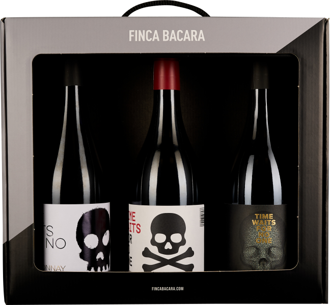 Drei Weinflaschen in schwarzer Box mit Totenkopf-Design auf Etiketten.