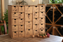 Adventskalender aus Karton mit natürlichen Illustrationen, auf einem Holztisch stehend.