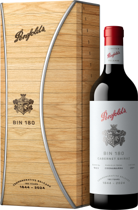 Weinflasche mit rotem Verschluss, eleganter weißer Etikettierung neben holzverpackter Geschenkbox.