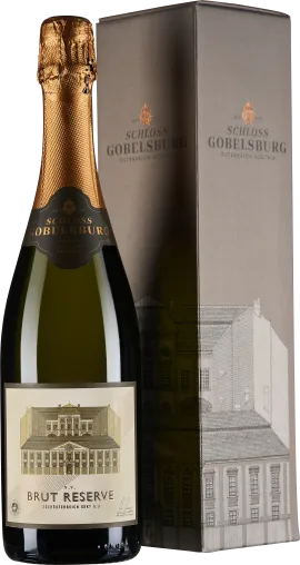 Flasche mit grünlichen, transparentem Glas und goldener Schaumweinkapsel, Etikett zeigt ein Schloss. Daneben eine schlichte, elegante Verpackung in Grau mit dezenten grafischen Linien des Gebäudes.