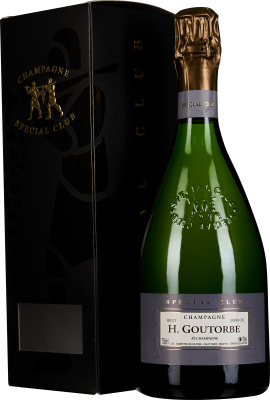 Grüne Champagnerflasche mit goldener Folie am Hals, verziert mit geprägtem Logo und lilafarbenem Etikett vor schwarzer Geschenkbox.