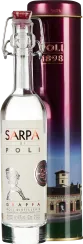 Klare, elegante Flasche mit Bügelverschluss, daneben eine metallische, rot-violette Geschenkbox mit goldenen Details und einem Bild einer Destillerie.