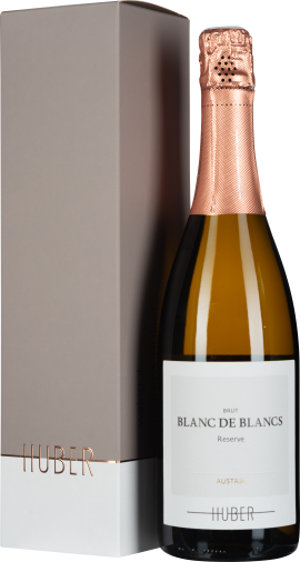Eine Sektflasche mit roségoldener Folie um den Flaschenhals, daneben eine elegante, zweifarbige, graue und weiße Geschenkverpackung mit kupferfarbenen Akzenten.