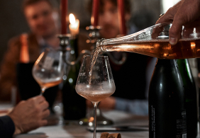 Weingläser auf gedecktem Tisch, Kerzenlicht schafft stimmungsvolle Atmosphäre.