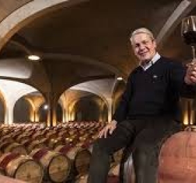 Mann hält Weinglas in einem Weinkeller mit vielen Fässern.