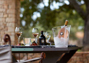 Gedeckter Tisch im Freien mit Weingläsern und einer Flasche im Eiskübel.