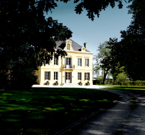 Helles Herrenhaus mit symmetrischen Fenstern, umgeben von gepflegtem Rasen und Bäumen.