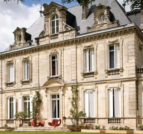Historisches Herrenhaus mit klassischer Fassade und großen Fenstern, umgeben von Garten.