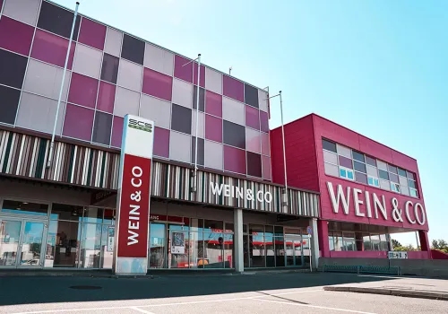 Modernes Gebäude mit Glasfassade und roten Paneelen, texturiertes Design.
