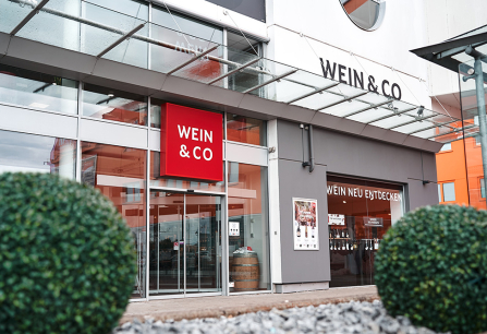 Moderne Ladenfassade mit gläsernem Eingang und großem roten Logo.