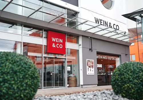 Moderne Ladenfassade mit gläsernem Eingang und großem roten Logo.
