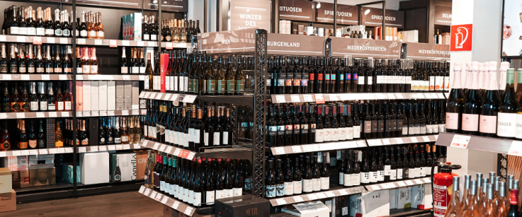 Weinladen mit gut beleuchteten Regalen voller verschiedener Weinflaschen.