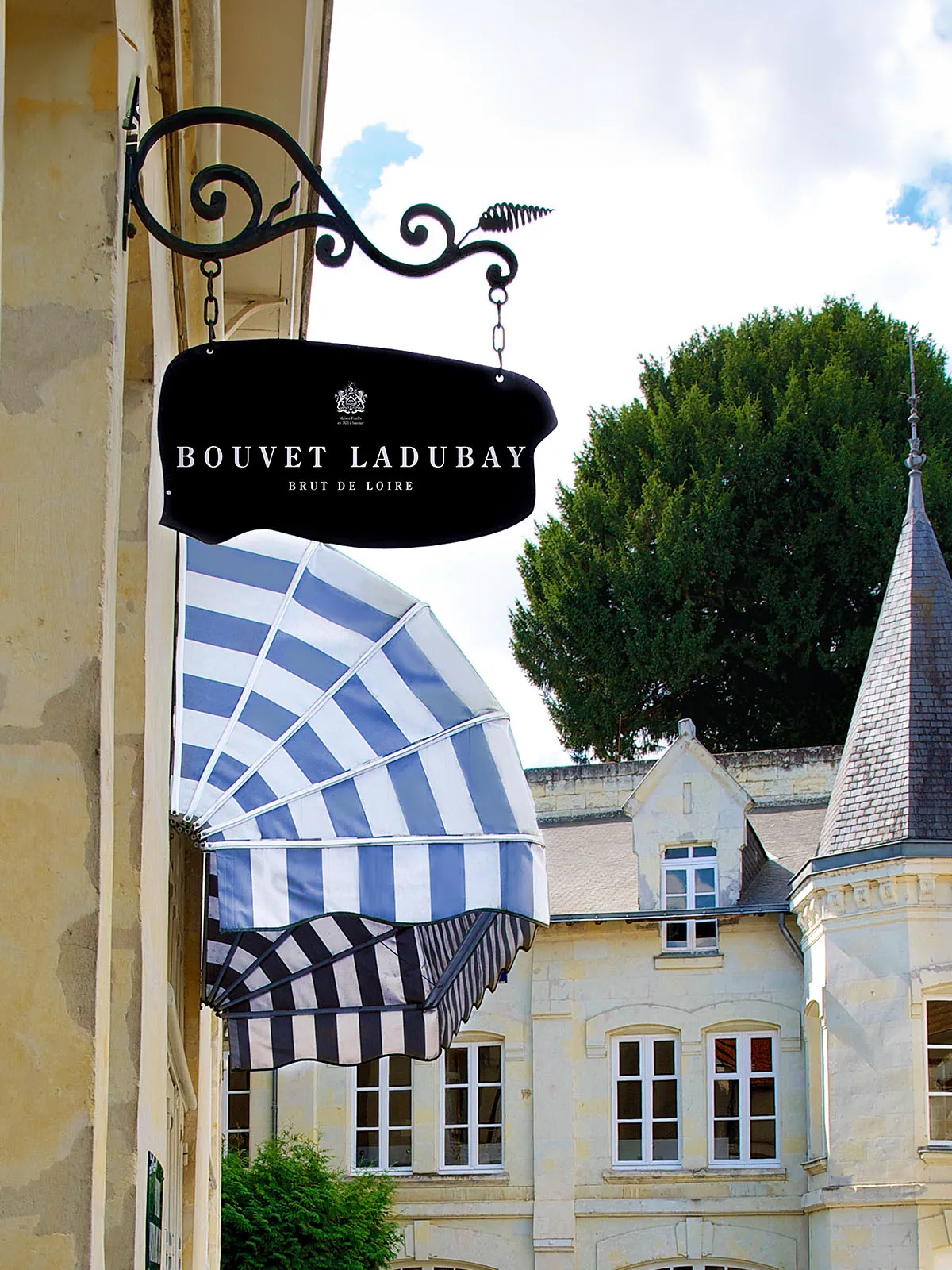Elegantes schwarzes Metallschild mit gestreifter Markise vor historischem Gebäude.
